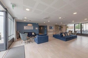 A spacious living area with a blue sofa set, a chair, and a dining table. - Nice apartment on the island of Ile de Ré (RIVEDOUX PLAGE)