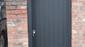 Een zwart metalen hek met een gebogen bovenkant, geplaatst in een bakstenen muur.