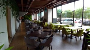 A restaurant with indoor seating, large windows, and a view of the street.