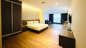 A modern hotel room with a large bed, a desk, and a TV.