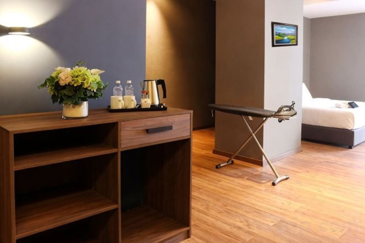 Una scrivania di legno con una pianta, una macchina da caffè e una bottiglia, un lettino da massaggio e un letto in una stanza con pavimento in legno.