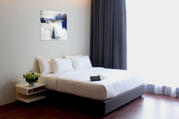 Une chambre d’hôtel moderne avec un grand lit, une table de chevet agrémentée d’une plante et un tableau au mur.