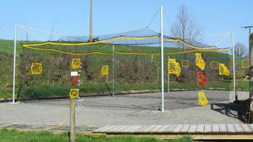 A sports field with a netted enclosure, wooden bleachers, and a grassy area.