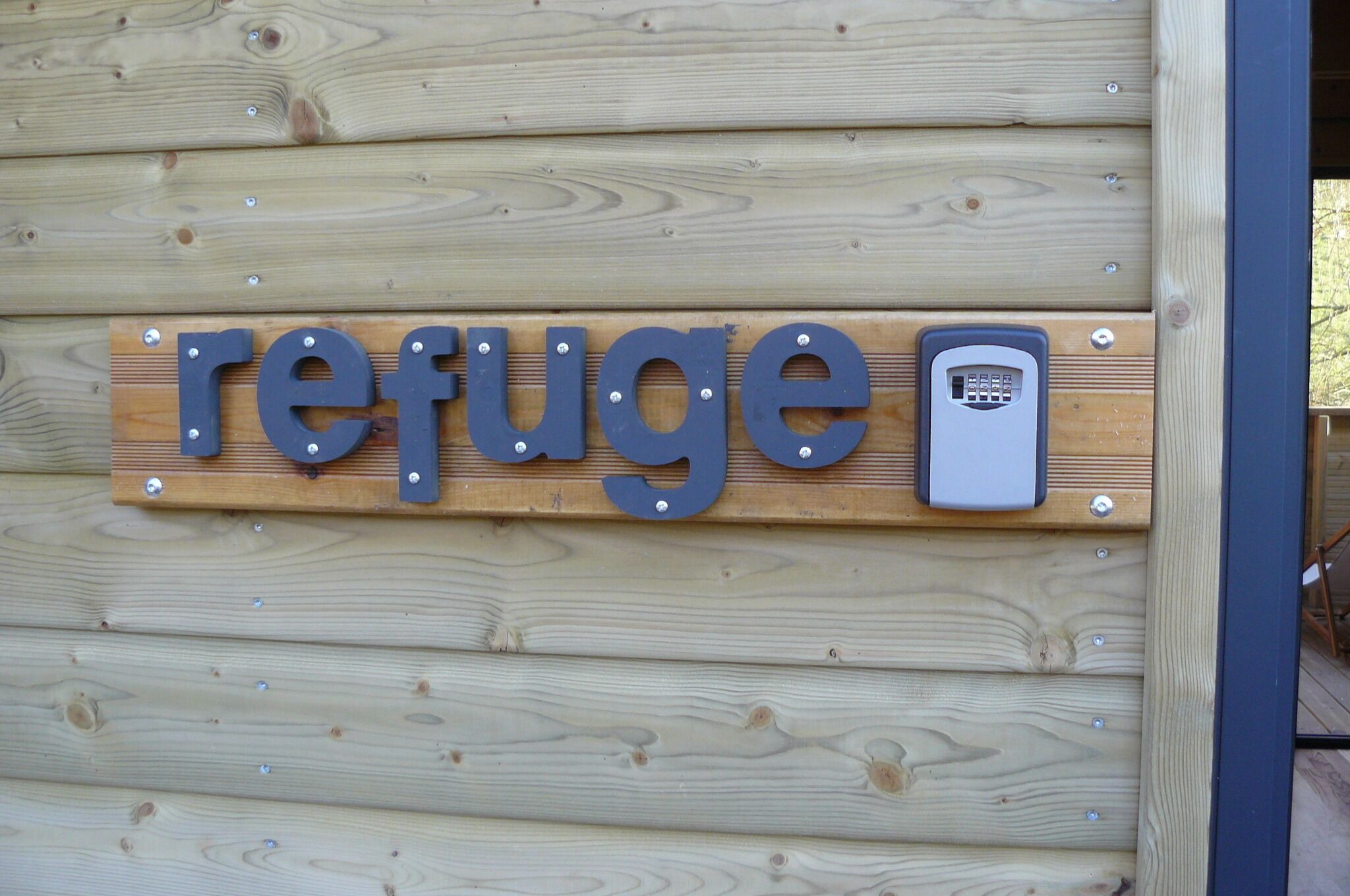 A wooden wall with the word "refuge" and a keypad.