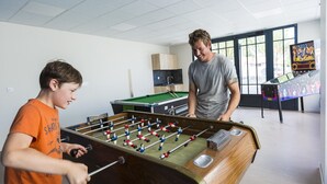 Ein Raum mit einem Kicker, einem Billardtisch und einer Jukebox.
