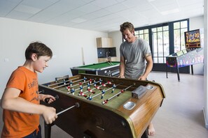 Ein Raum mit einem Kicker, einem Billardtisch und einer Jukebox.