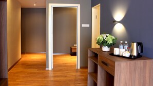 Habitación de hotel con piso de madera, un mostrador de recepción con planta y una lámpara fijada en la pared.