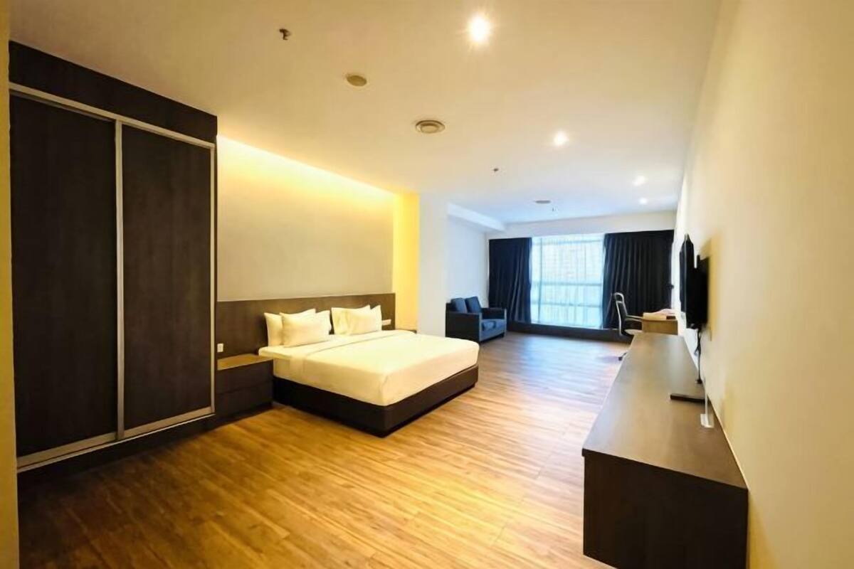 Habitación de hotel con una cama grande, un escritorio, un televisor y un armario.