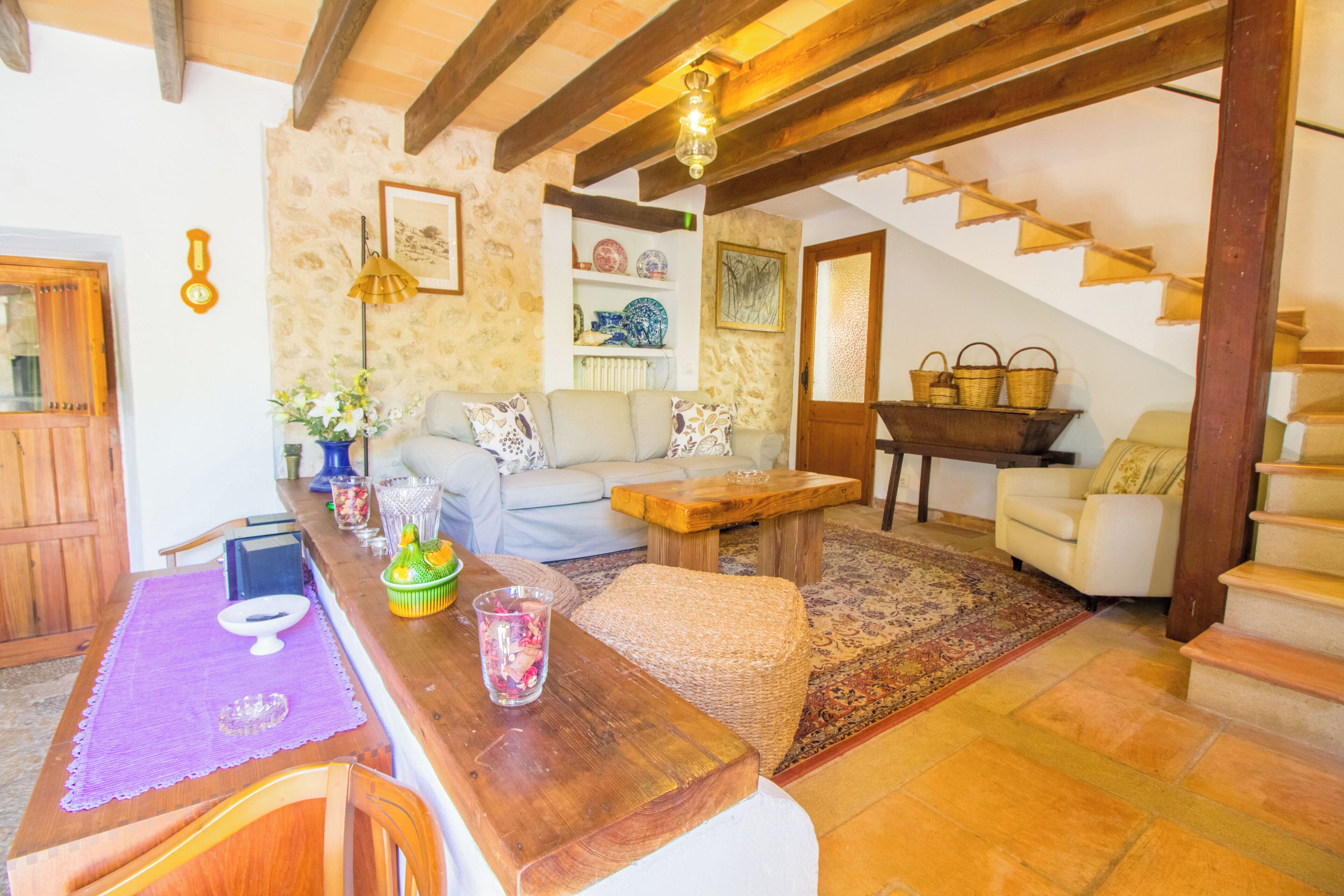 Una sala acogedora con una mesa de madera, un sofá y una escalera que sube a otro nivel.