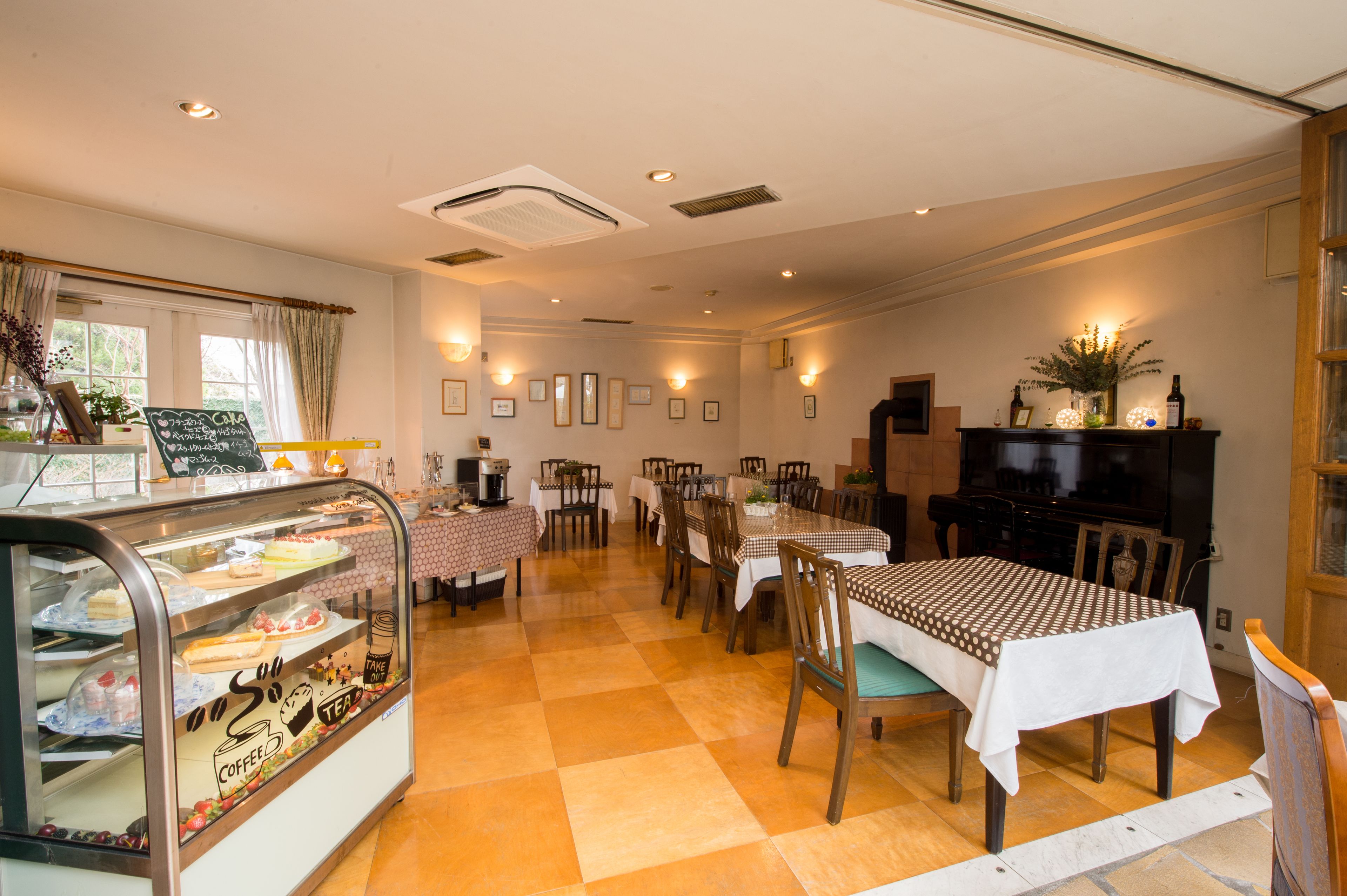 Un'area dedicata alla ristorazione con un bancone che espone pasticcini e una macchina per caffè. Sono presenti diversi tavoli e sedie disposti per i pasti.