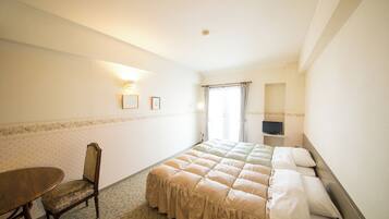 A hotel room with a bed, a chair, a table, and a television.