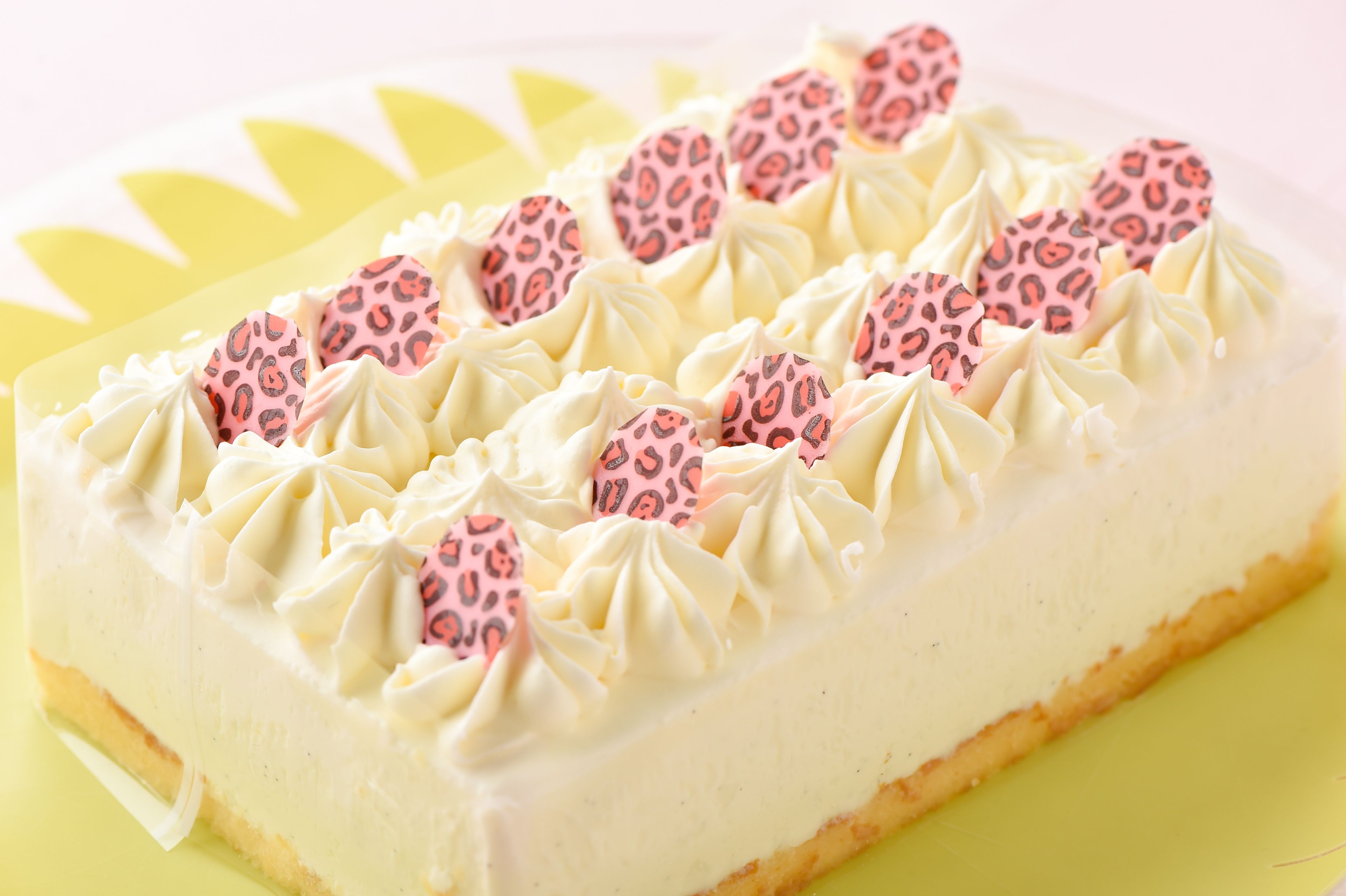 A cheesecake with pink patterned decorations on a yellow plate.