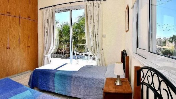 Quarto com duas camas, guarda-roupa de madeira, espelho e janela com cortinas.