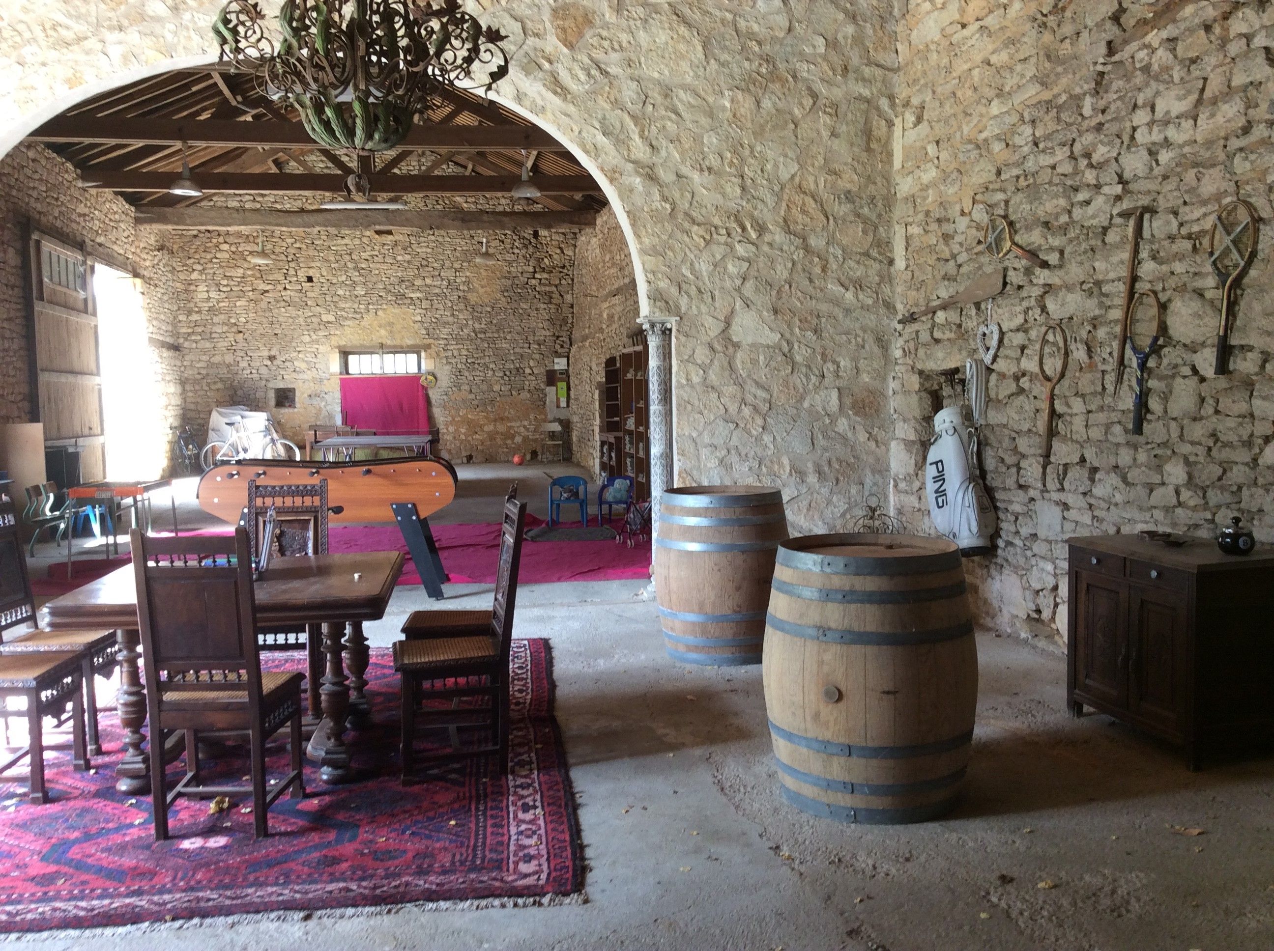Ein rustikales Interieur mit Steinwänden, Holzmöbeln und Fässern.