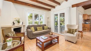 Una sala de estar con sofá, sillón, mesa de centro y chimenea.