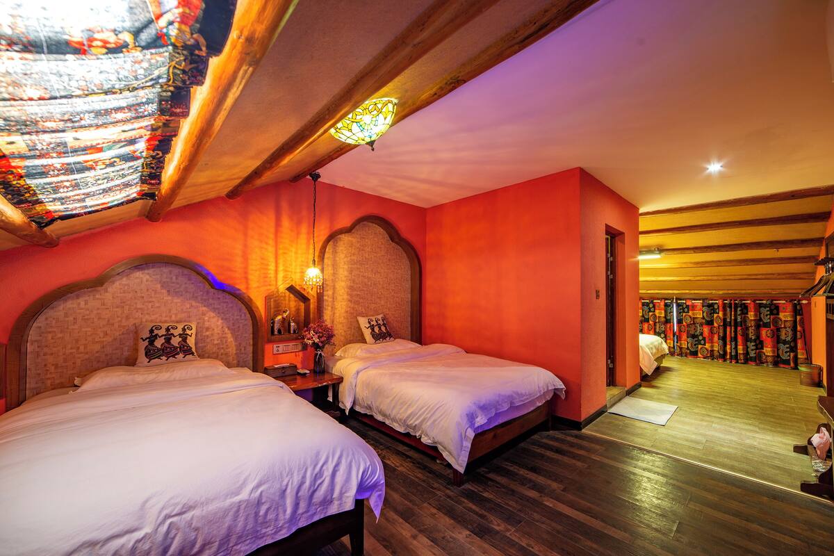 Ein Hotelzimmer mit zwei Betten, Holzboden und einer Deckenleuchte aus Buntglas.