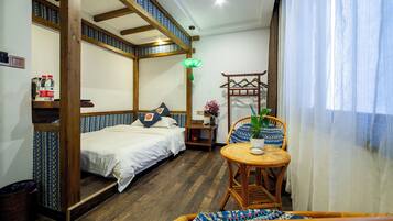A room with a bed, a small table with a plant, and a chair.