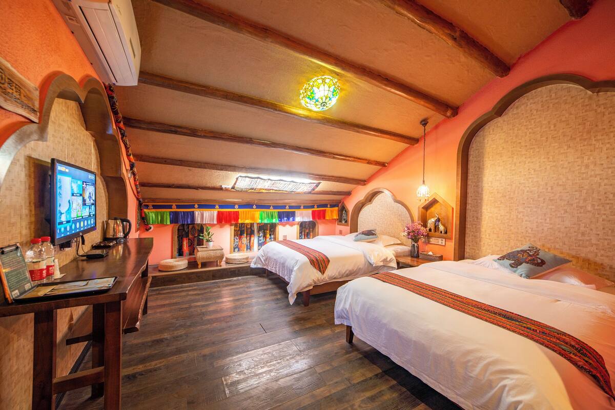 Ein Hotelzimmer mit zwei Betten, einem Schreibtisch mit Computer und einem Fernseher.