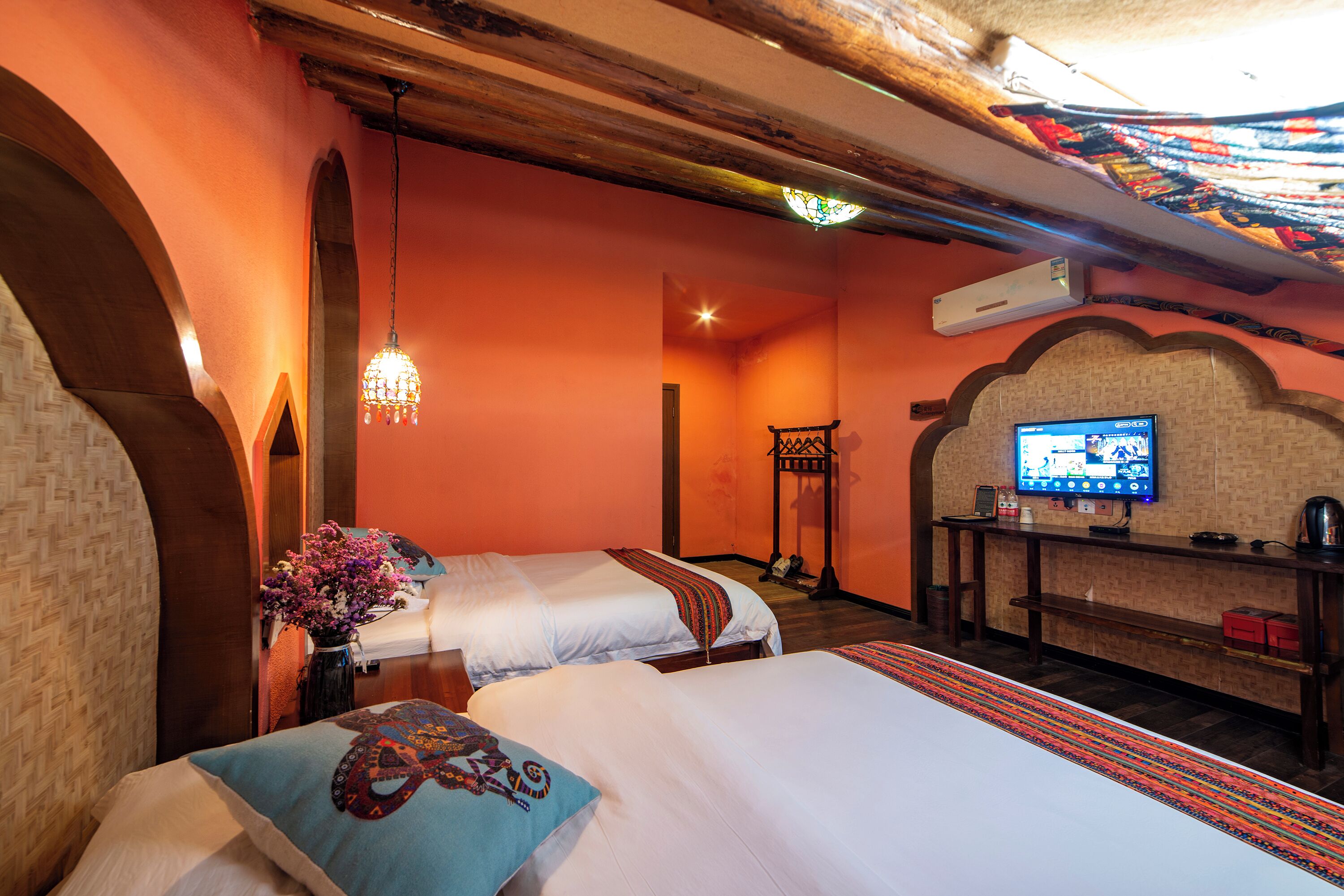 Habitación de hotel con dos camas, un televisor, una mesita pequeña y un detalle decorativo en la pared.