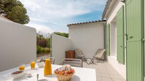 Eine Terrasse mit Tisch, gedeckt für ein Frühstück, inklusive Schüsseln mit Müsli und einem Korb mit Croissants, sowie einem Stuhl.