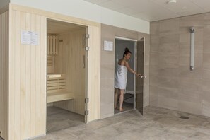 Un sauna avec un banc en bois et une porte en verre.