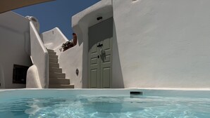 A clear swimming pool with a white building in the background, a door, and a window. - Traditional Village House 'Alba Lily' with heated plunge pool (Megalochori)