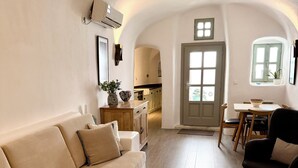 A cozy interior with a sofa, a dining table with chairs, and a kitchen in the background. - Traditional Village House 'Alba Lily' with heated plunge pool (Megalochori)