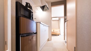 A narrow hallway with a refrigerator, a microwave, and a small kitchenette area.