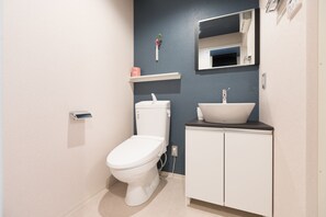A modern bathroom with a toilet, sink, and mirror. - Stay SAKURA Kyoto Nijo Seasons (Kyoto)