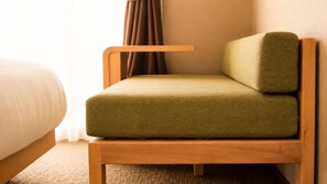 A single bed with a wooden frame, a green upholstered chair with a wooden base, and a brown curtain. - Stay SAKURA Kyoto Nijo Seasons (Kyoto)