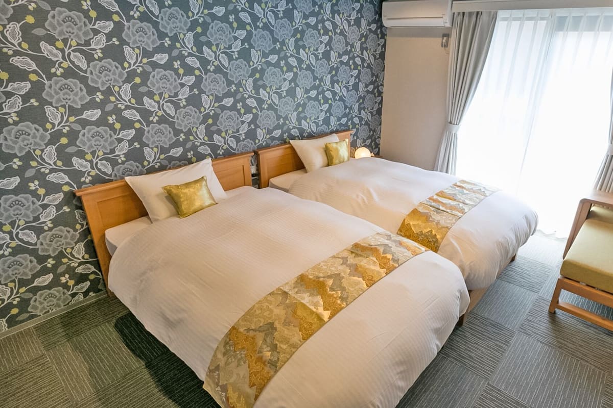 A double bed with a floral-patterned headboard, a bedside table, and a chair.