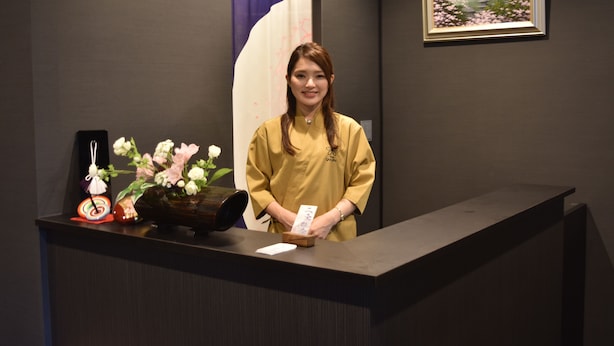 A reception desk with a vase of flowers, a framed picture on the wall, and a sign above the door.