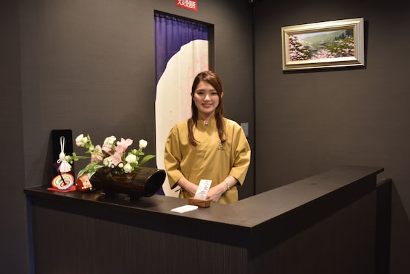 A reception desk with a vase of flowers, a framed picture on the wall, and a sign above the door. - Stay SAKURA Kyoto Nijo Seasons (Kyoto)