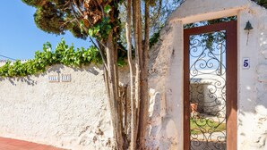 Eine Villa mit rustikalem Äußeren, einer Holztür mit schmiedeeisernem Tor und einem an der Wand angebrachten Schild mit der Nummer 5.