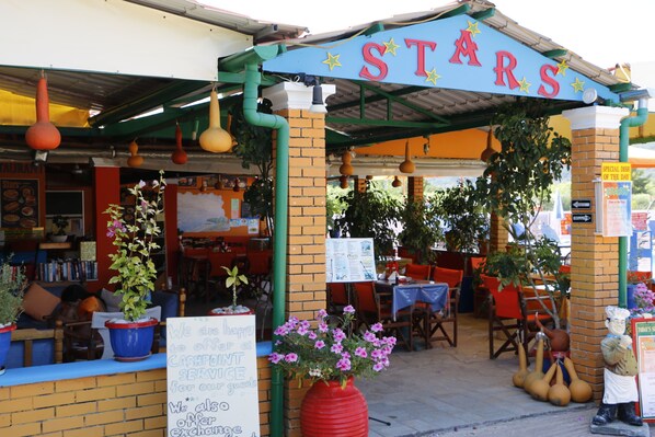 A restaurant named 'STARS' with outdoor seating, a cash-only service sign, and a menu board.