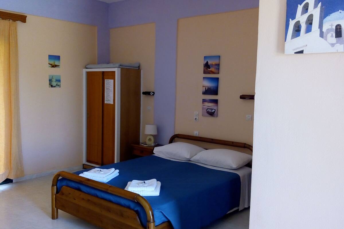 A hotel room with a bed, a wardrobe, a nightstand, and a lamp.