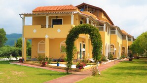 A yellow building with a red-tiled roof, multiple balconies, and a central archway. - Stars Hotel - Adults Only (Corfu)