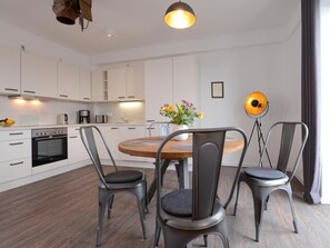 A modern kitchen with white cabinets, a wooden dining table, and two metal chairs.