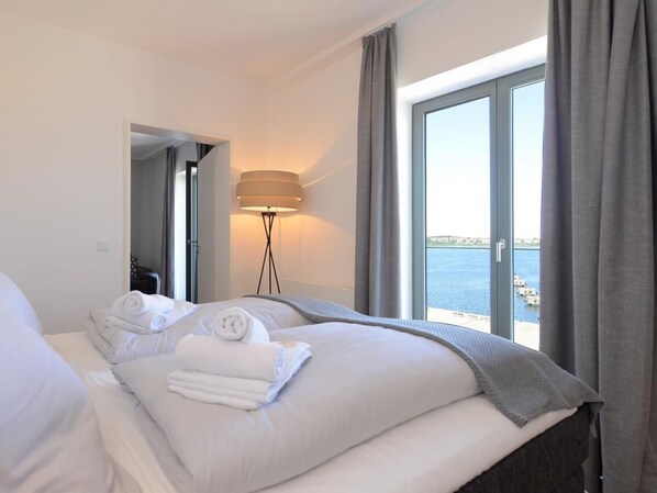 A hotel room with a bed, a lamp, and a view of the sea.