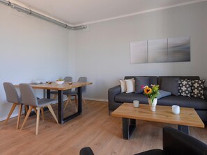 A modern living room with a dining area, a sofa with decorative pillows, and a coffee table.