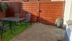 Eine Terrasse mit Tisch und Stühlen, einem Holzzaun und einem Blumentopf.