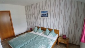 Ein Schlafzimmer mit einem Bett, einem Nachttisch, einer Lampe, einem Bild an der Wand und einem Wandpapier mit Muster.