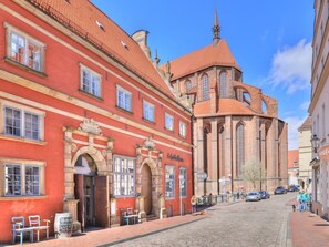 A historic building with a red facade and a church with a red roof.
