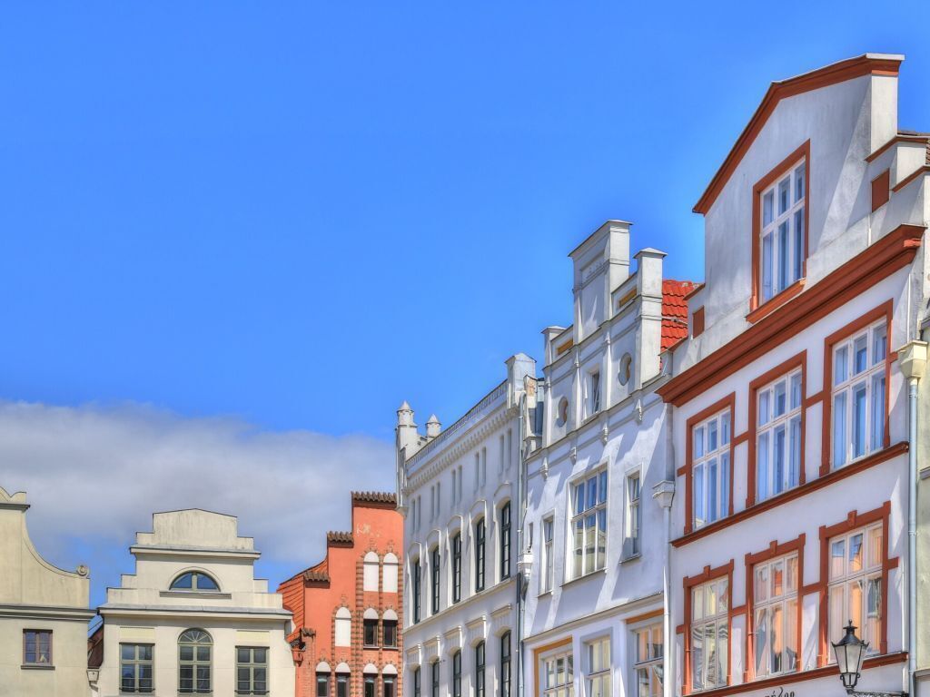 A row of historic buildings with distinct architectural styles, including a red brick building and a white building with red trim.