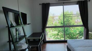 A hotel room with a bed, a desk, a chair, a TV, and a window with curtains.