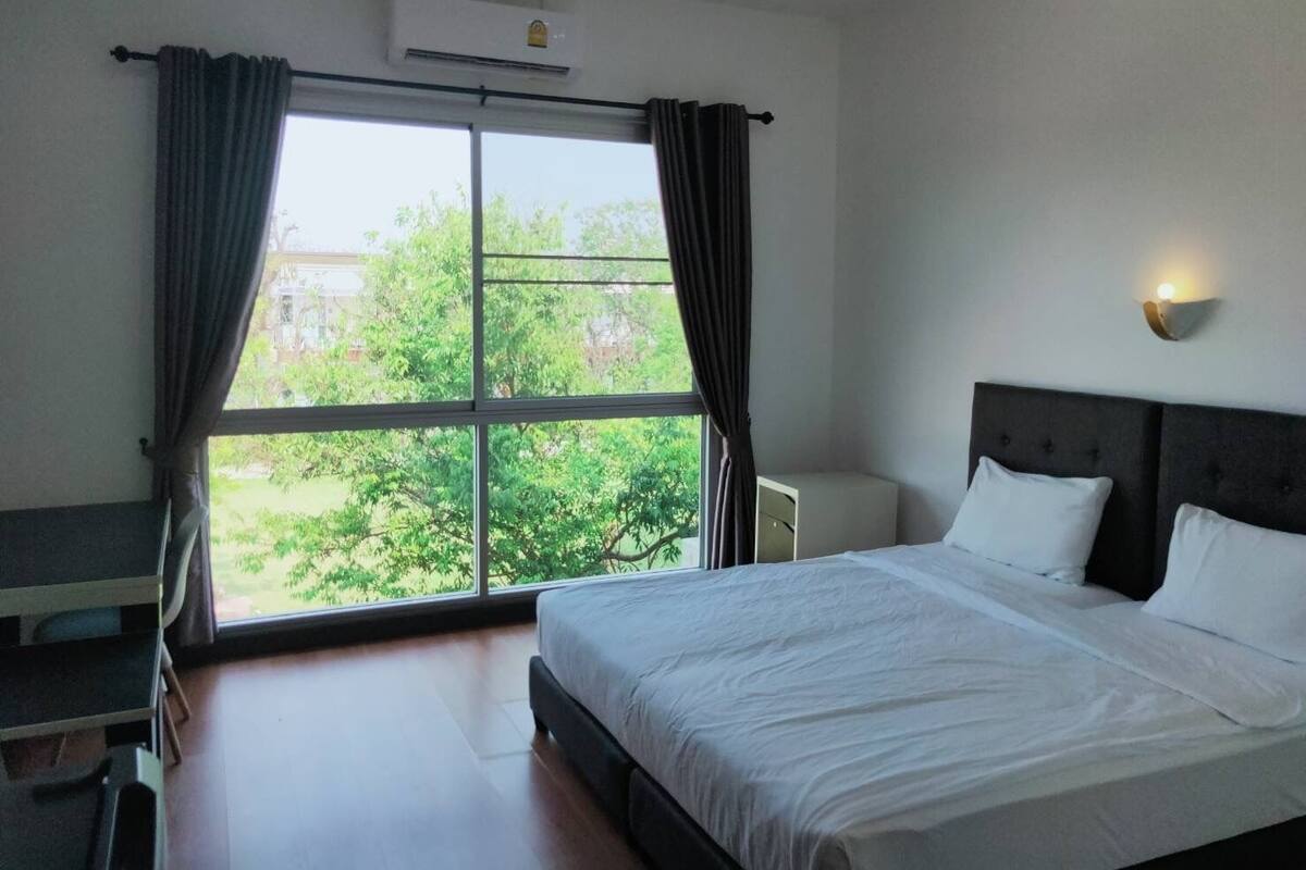 A hotel room with a large bed, a desk, and a window with curtains.