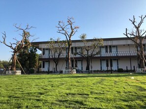 Um edifício com telhado plano, várias janelas e uma cerca branca na frente.