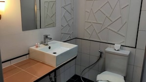 Une salle de bain moderne avec un lavabo, un miroir et des toilettes, le tout de couleur blanche.