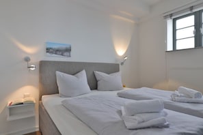 A hotel room with two beds, a nightstand, a wall-mounted picture, and a window with blinds. - Ohlerich storage app. 33 - Ohlerich Speicher App. 33 (Wismar)