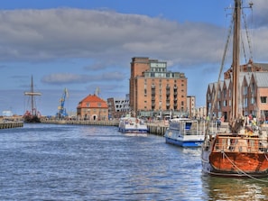 A harbor with boats, a red-roofed building, and a tall structure with cranes. - Ohlerich storage app. 33 - Ohlerich Speicher App. 33 (Wismar)